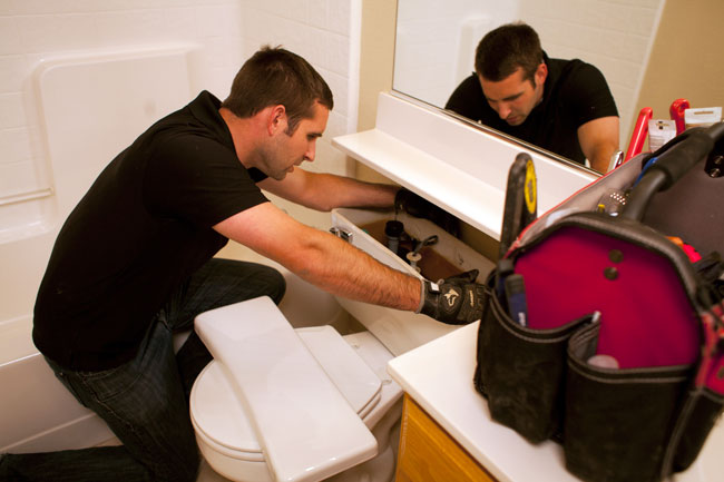 Plumber removes a tank lid for a toilet repair in Fresno